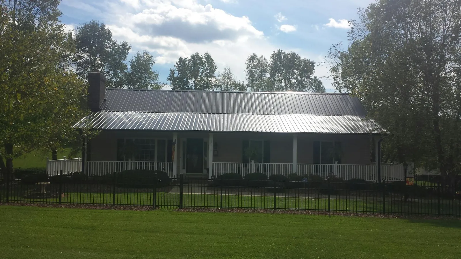 Gray metal roof on a brick ranch with a full width front porch — Gutter Guard Installation work by our crew in Piney Woods