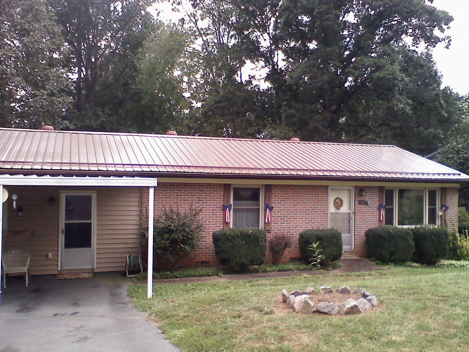 Bronze metal roof and carport on a brick ranch home — Roof Repair work by our crew in Piney Woods